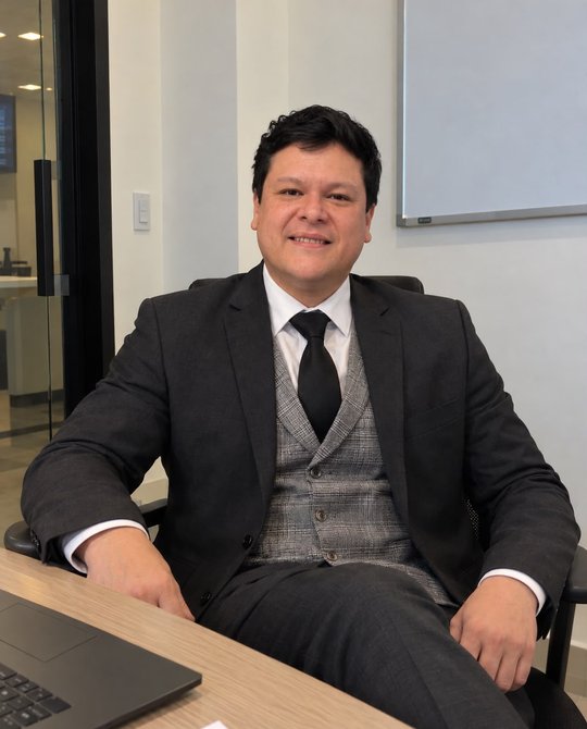 Dr. David Alejandro Viscarra sentado en su escritorio, vestido de traje.